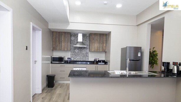 Una cucina moderna con isola centrale, elettrodomestici in acciaio inossidabile e una parete di fondo decorata.