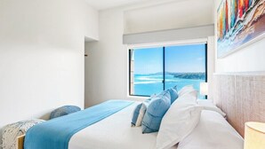 A bedroom with a large window offering a view of the sea and hills. - Oceanfront Eagle’s Nest - Bali Hai Sunset Views (Princeville)