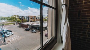 Blick durch ein Fenster auf einen Parkplatz mit einem Gebäude im Hintergrund, auf dem 'Second State Brewing' steht.