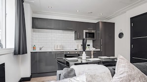 A modern kitchen with grey cabinets, a white tiled backsplash, and a black oven.