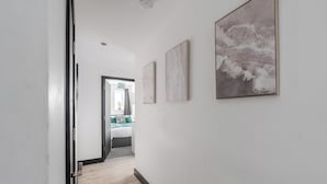 A hallway with a wooden floor, white walls, and three framed artworks.