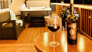 Eine Holzterrasse mit Tisch, einer Weinflasche und einem Weinglas.