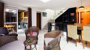 Un saló modern amb moble de vimet, una zona de dinar i una escala que condueix a una cuina.