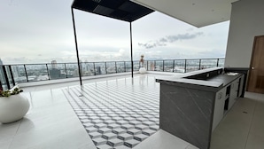Et moderne køkken med en stor ø, en balkon med udsigt over byen og et gulv med geometrisk mønster.