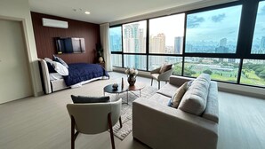 Et moderne hotelværelse med en stor seng, en sofa, et sofabord og et fjernsyn.