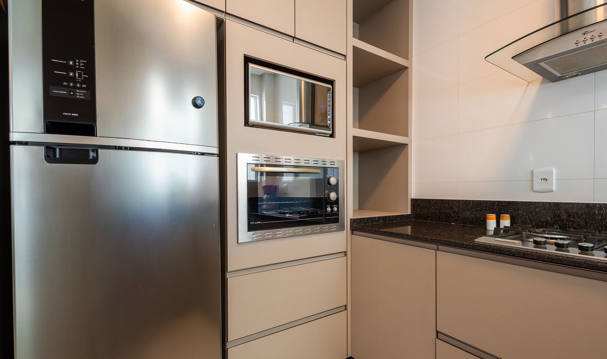 A kitchen with a stainless steel refrigerator, a built-in oven, and a microwave.