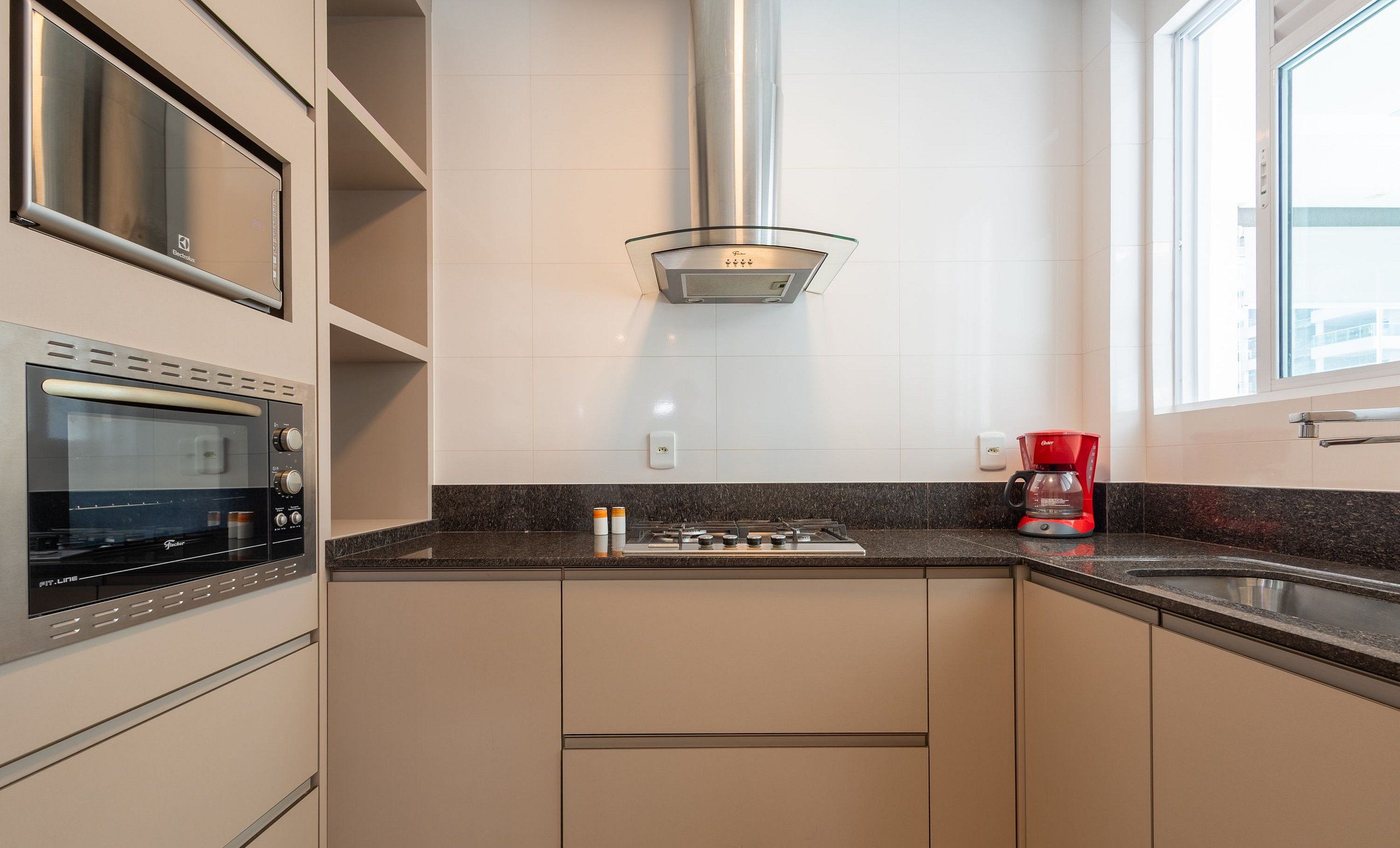 A modern kitchen with a built-in oven, a gas stove, and a coffee maker.