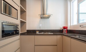 A modern kitchen with a built-in oven, a gas stove, and a coffee maker. - Apt w/ Gourmet Balcony 450m From Beach Reb0802 (Itapema)