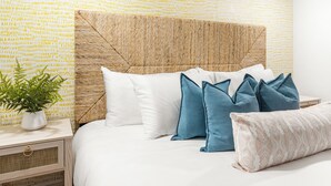 A neatly made bed with white and blue pillows, a woven headboard, and a patterned wall. - Pool, Hot Tub, Pickleball, Game Room & Spacious for Groups - Near Beach! (Gulfport)