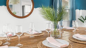 A dining table set with wine glasses, plates, and napkins, surrounded by woven placemats and a potted plant. - Pool, Hot Tub, Pickleball, Game Room & Spacious for Groups - Near Beach! (Gulfport)