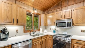 Une cuisine dotée de meubles en bois, d’appareils électroménagers en acier inoxydable et d’une fenêtre donnant sur un paysage verdoyant.