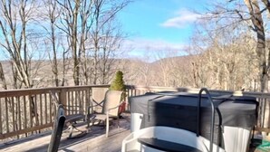 A wooden deck with a hot tub, chairs, and a small tree. - Modern comfort with mountain charm! (Mars Hill)