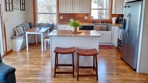 A modern kitchen with a central island, bar stools, and a dining area with a bench. - Modern comfort with mountain charm! (Mars Hill)