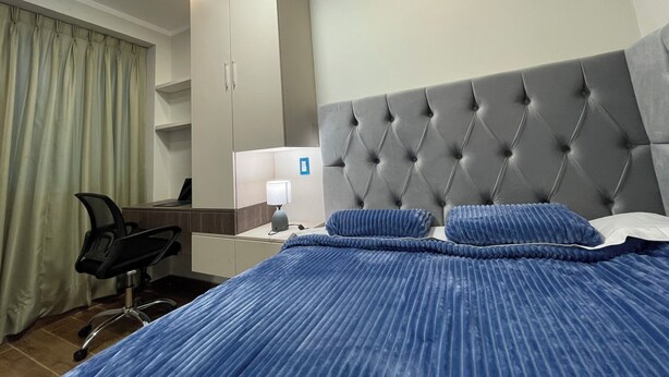 Ein Hotelzimmer mit Bett, Schreibtisch, Stuhl und Kleiderschrank.
