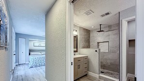Een moderne badkamer met een inloopdouche, een wastafel met spiegel en een houten vloer.