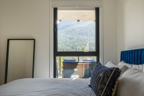 Ein Schlafzimmer mit einem großen Fenster, einem Bett und einem blauen Kopfteil.