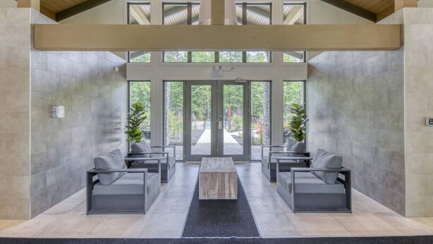 A modern interior with a high ceiling, large windows, and a central seating area with sofas and a coffee table. - The Axia at Verbier: Hot Tub, Sauna, Seasonal Pool (Mont-Tremblant)