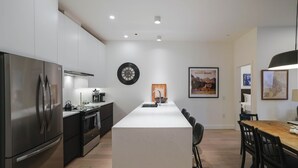 Eine moderne Küche mit einer zentralen Kochinsel, Edelstahlgeräten und einem Essbereich mit einem Holztisch und Stühlen.