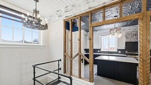 A modern kitchen with a large island, a built-in oven, and a hanging light fixture.