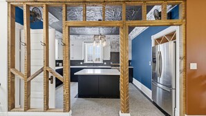 A modern kitchen with a central island, stainless steel appliances, and a view into the dining area.