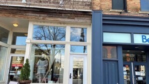 A storefront with a large window display, a door with a sign, and a building number.