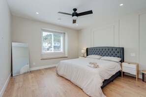 A bedroom with a bed, a ceiling fan, a window, and a nightstand. - Splendid Home in Victoria (Langford)