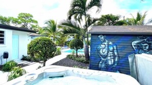 Zona de hidromasaje con un mural, una piscina y palmeras.