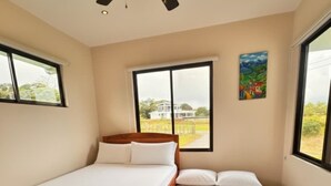 A bedroom with a bed, a ceiling fan, and large windows. - Lake Sunset House in Arenal-quiet retreat spectacular views (Tilaran)
