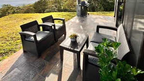 A covered patio with wicker furniture, a grill, and a view of the landscape. - Lake Sunset House in Arenal-quiet retreat spectacular views (Tilaran)
