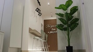 A modern interior with a wooden panel wall, a metal chair, a large potted plant, and a ceiling light fixture. - Cozy and equipped with amenities, for couples and families in a quiet setting. (Napoli)