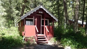 A cabin with a red exterior, a porch, and a staircase leading to the entrance. - Madison River Cabin Rental #2 (W YELLOWSTONE)