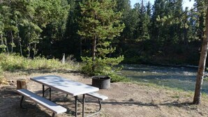 Ett picknickbord i ett skogsområde med en flod i bakgrunden.