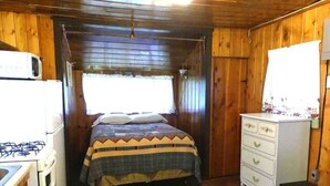 Una habitación pequeña y acogedora con cama, cómoda, estufa y ventana.