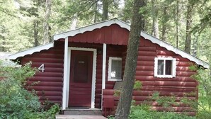 Una cabaña rústica con puerta roja, número 4, rodeada de un bosque denso.