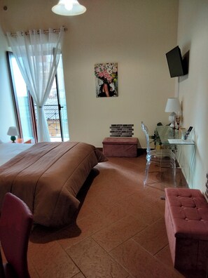 A bedroom with a bed, a desk, a chair, a TV, and a window with curtains. - Atena Apartments Agrigento Centro (Agrigento)