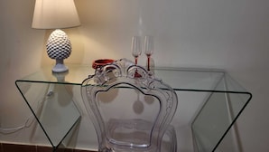 A glass table with a clear glass vase and two wine glasses.