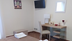 A hotel room with a bed, a desk, a chair, a TV, and a window.