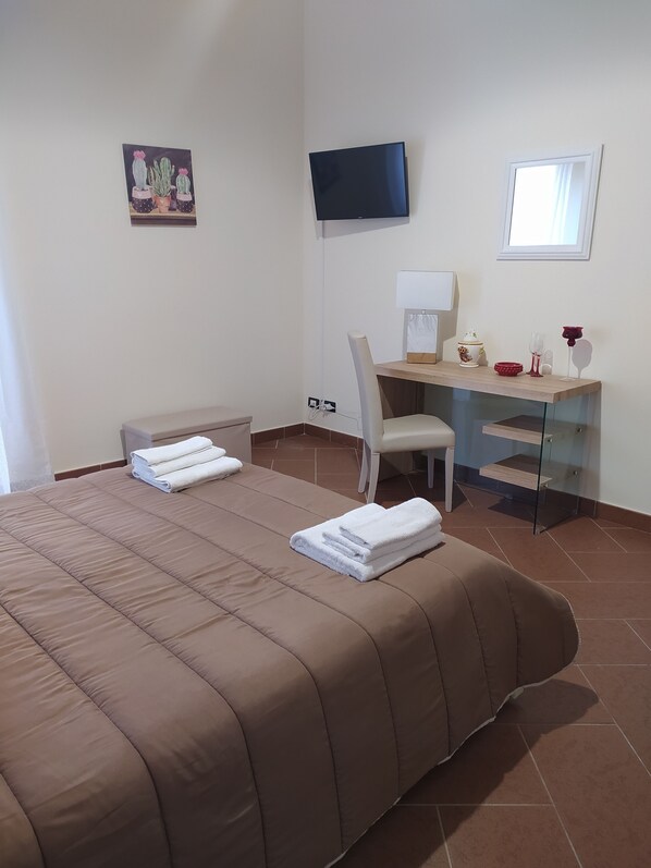 A hotel room with a bed, a desk, a chair, a TV, and a window. - Atena Apartments Agrigento Centro (Agrigento)