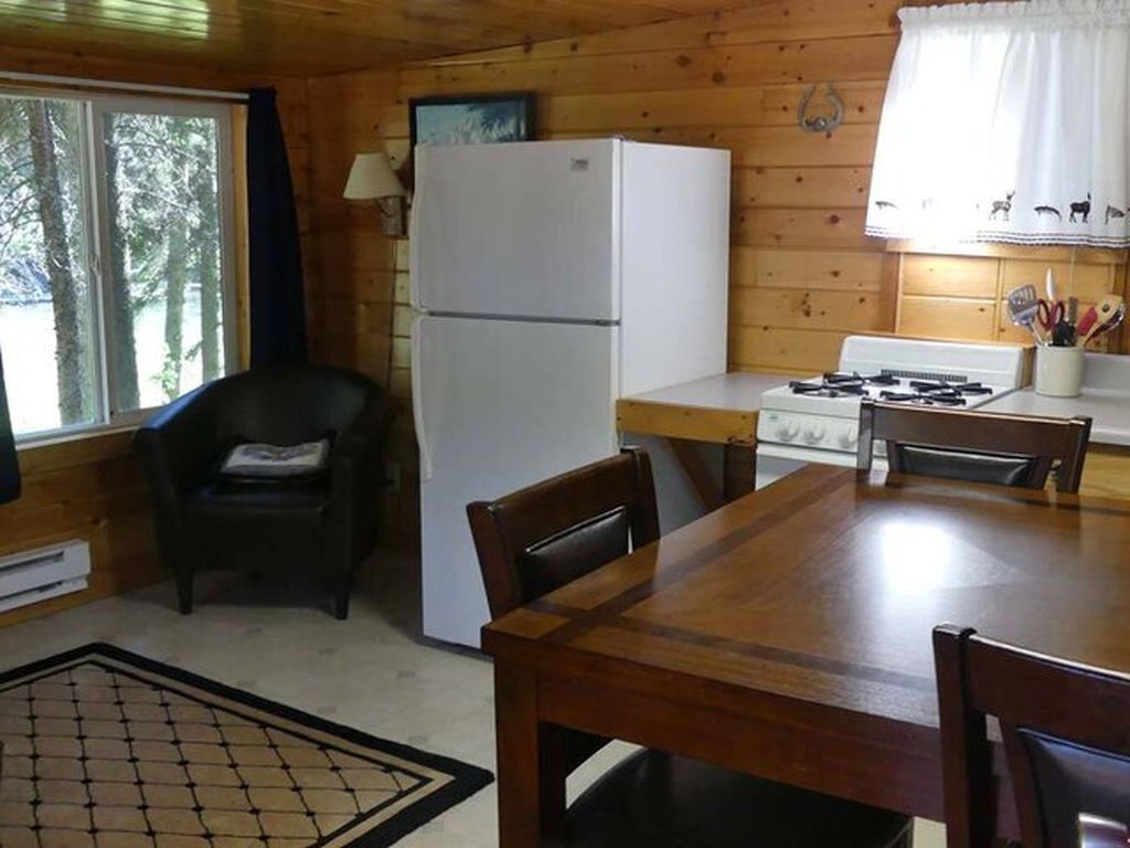 A wooden cabin kitchen with a refrigerator, stove, and dining table.