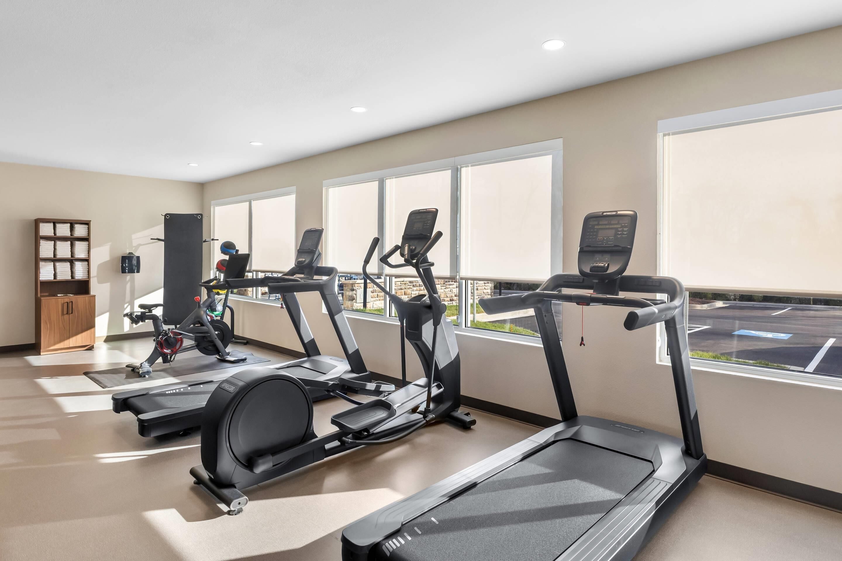 A gym with treadmills, elliptical machines, and a weight bench.
