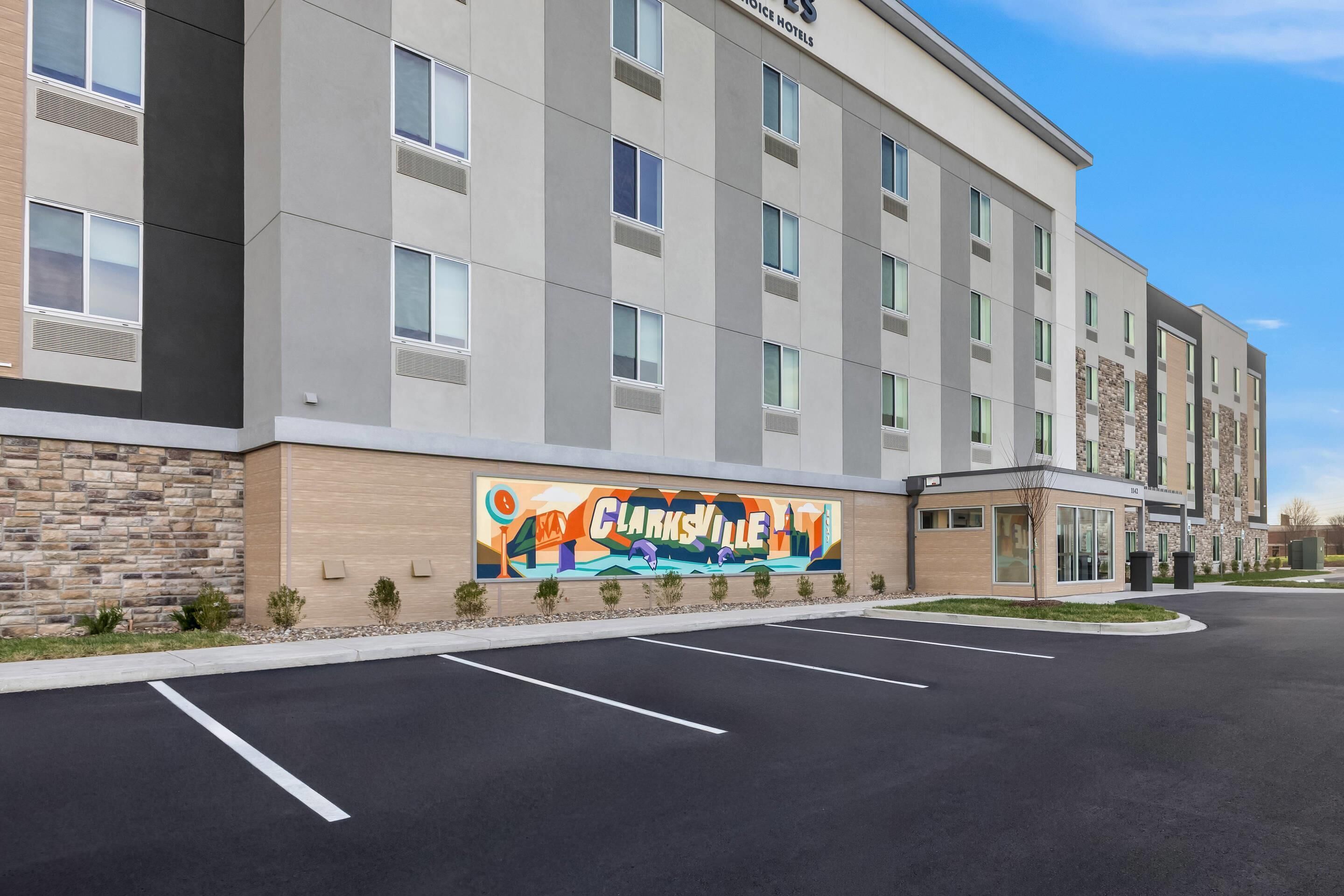 A modern hotel building with a parking lot in front.