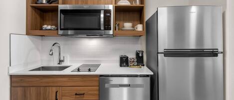 Una cocina moderna con microondas de acero inoxidable, refrigerador y lavavajillas.