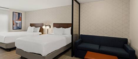 A hotel room with two beds, a sofa, a small table, and a wall with geometric patterns.
