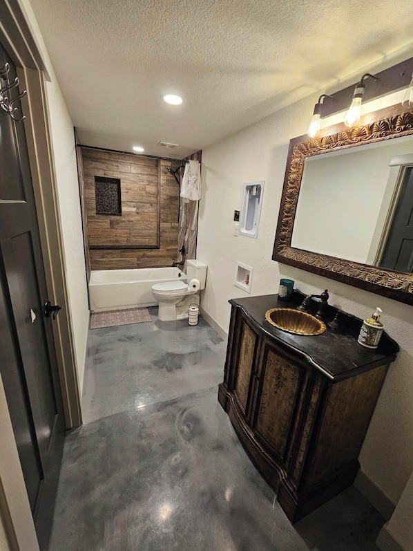 A modern bathroom with a bathtub, toilet, and vanity. - The 4-bedroom Brook House Barndominium is the perfect space for you! (Colorado Springs)