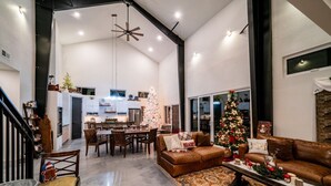 A spacious living area with a large Christmas tree, a brown leather sofa, and a dining table set for six. - The 4-bedroom Brook House Barndominium is the perfect space for you! (Colorado Springs)