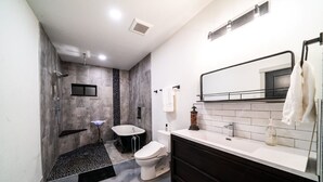 A modern bathroom with a shower, bathtub, toilet, and vanity. - The 4-bedroom Brook House Barndominium is the perfect space for you! (Colorado Springs)