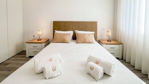 Une chambre d’hôtel avec un grand lit, deux tables de chevet et une tête de lit en bois.