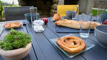 Une table dressée avec de la nourriture et des boissons, notamment des pâtisseries, un croissant et des verres.