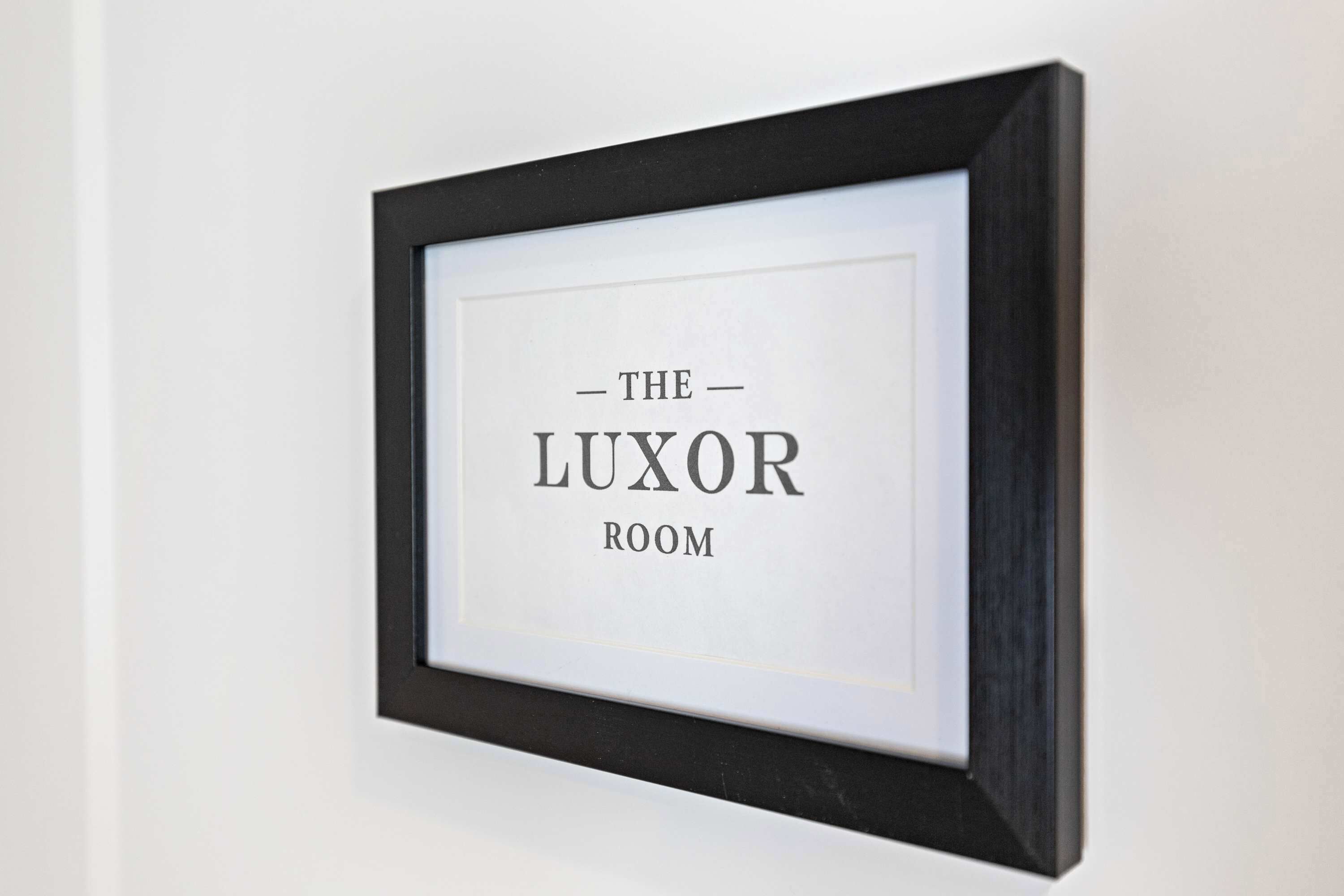 Een lijst met de tekst 'THE LUXOR ROOM'.