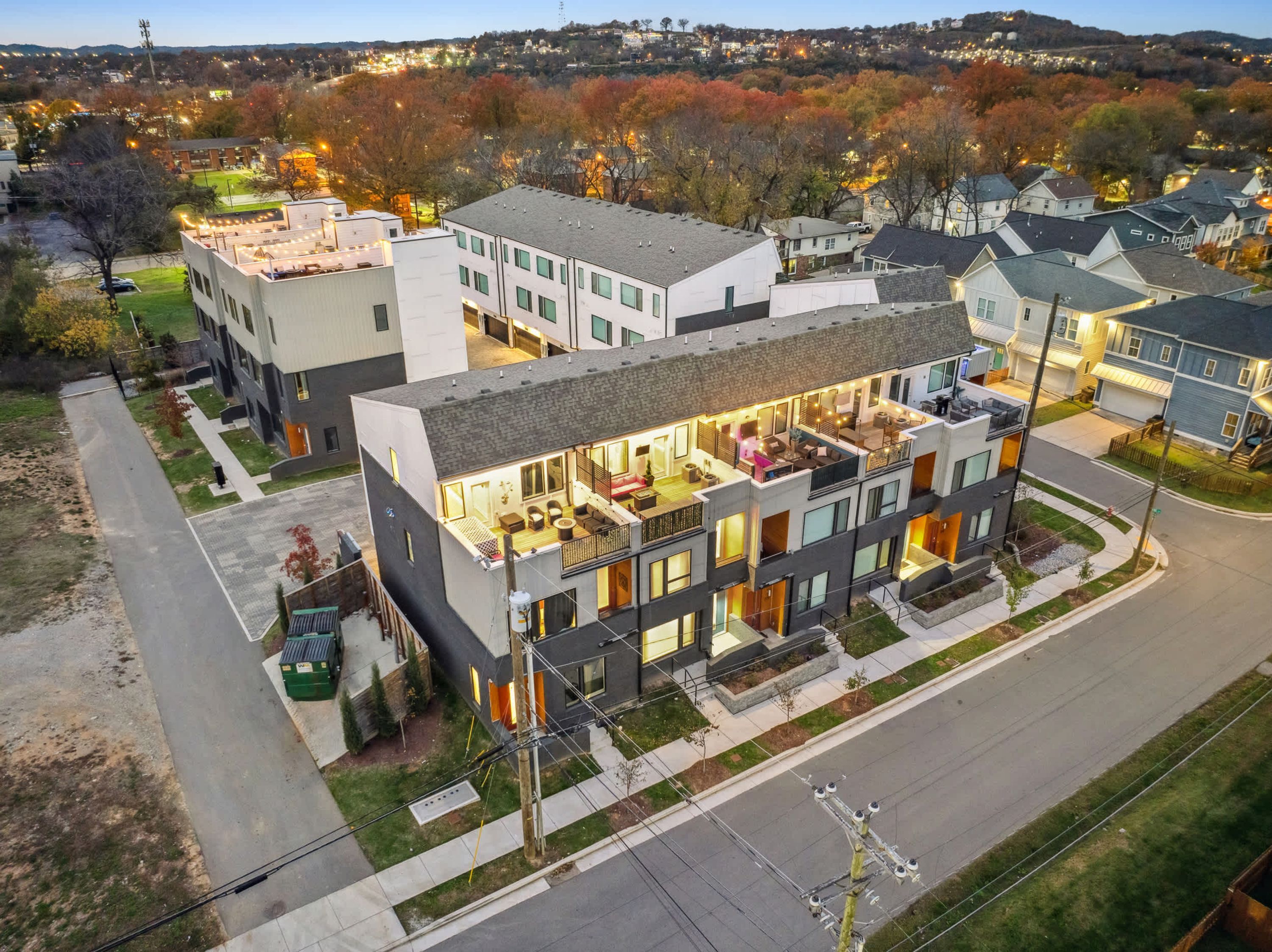 A modern multi-story residential building with a spacious balcony area, a driveway, and a well-maintained lawn.
